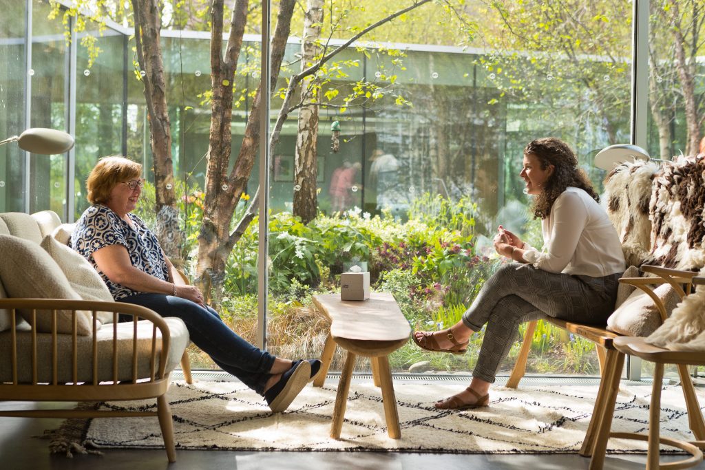 Two people in front of internal courtyard plantings of Maggie's, Glasgow - designed by Lily Jencks.